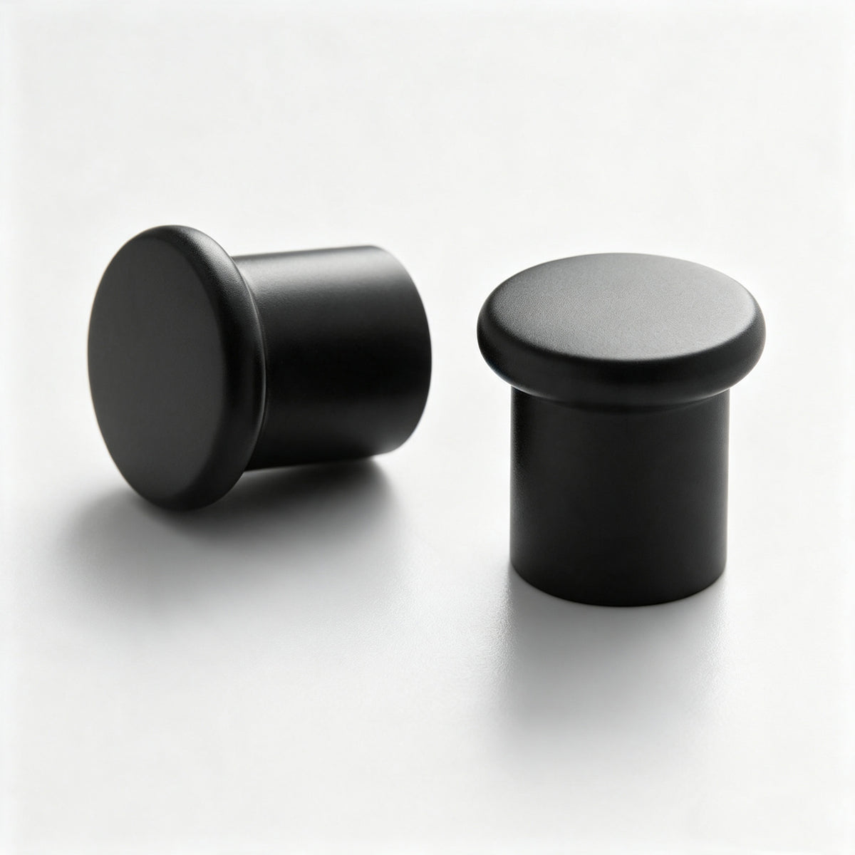Black round cabinet knob on a white background